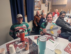 Emma Hanson holds her table's runner-up prize for finishing second in the holiday party trivia contest