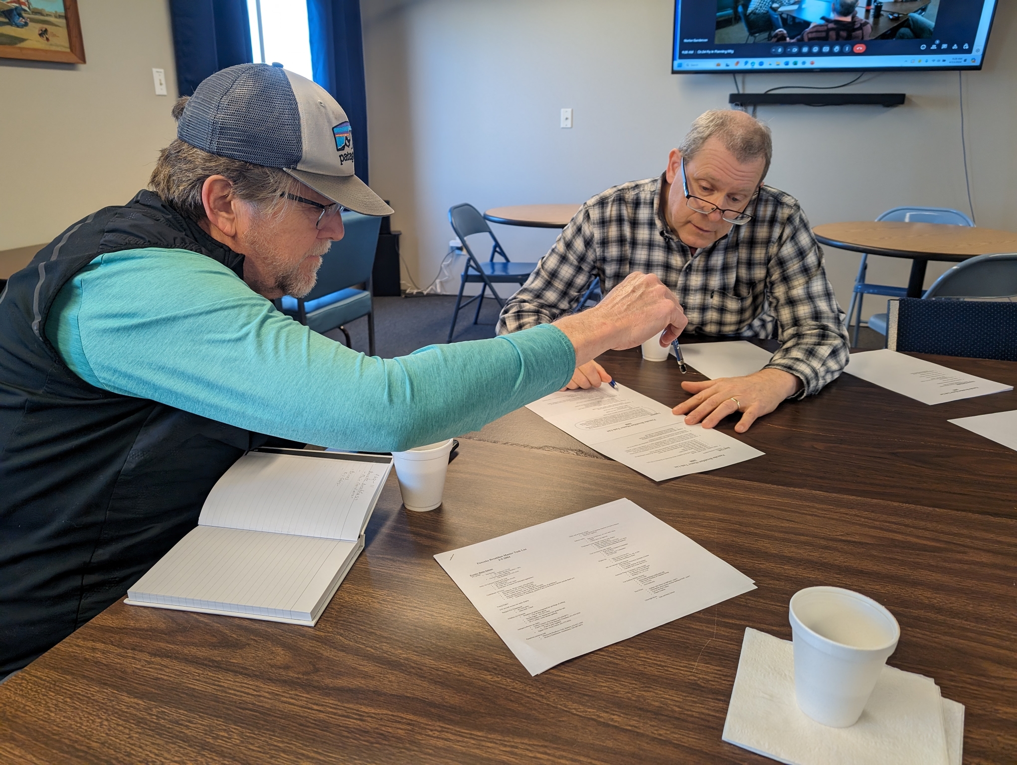 Jim Pearsall, left, and Marlon Gunderson, right, go over a list of duties for volunteers at a planning event on April 13, 2024 for a pancake breakfast fly-in in August.