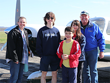 5 people standing in front of an airplane