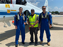 two astronauts and one ground crew standing in front of a jet