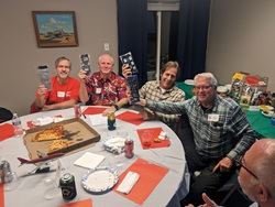 The winning trivia team shown around a table holding up their prize: socks.