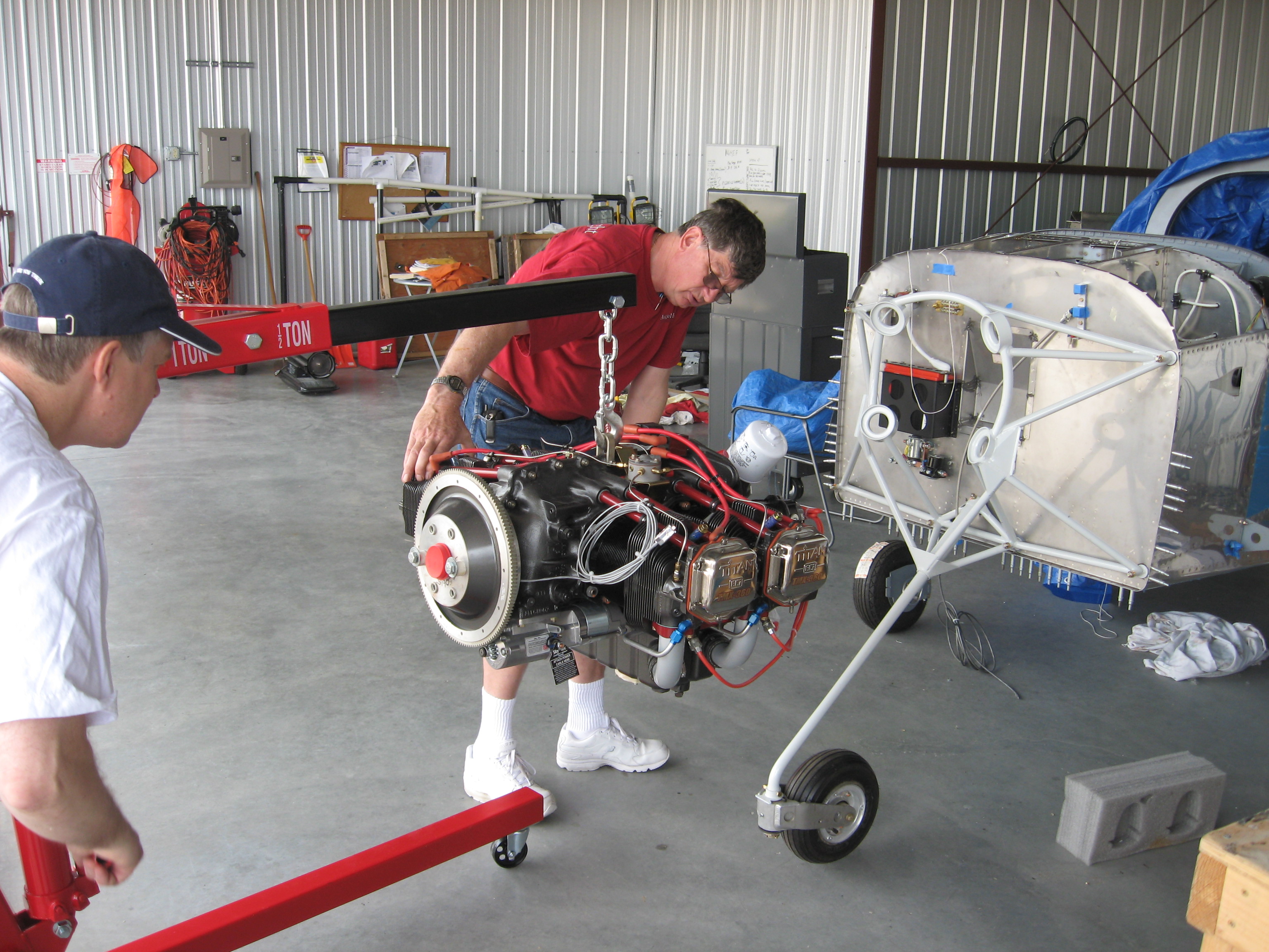 Bob Collins and Gary Speketer move an IO360M1B engine into position on an RV7A